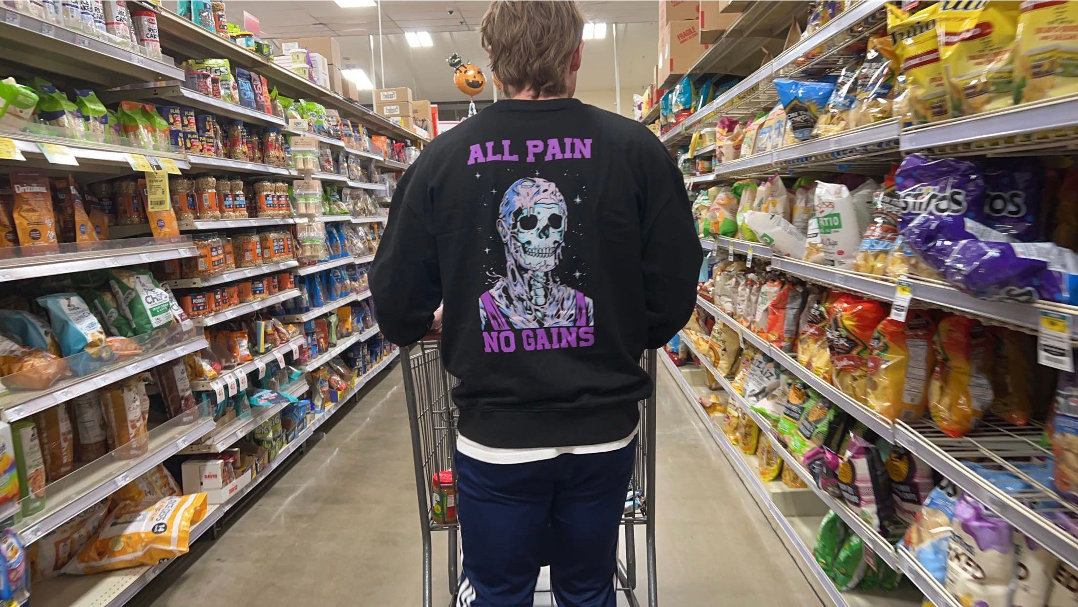 brandon wells in a grocery store wearing a sweatshirt that says ALL PAIN NO GAINS
