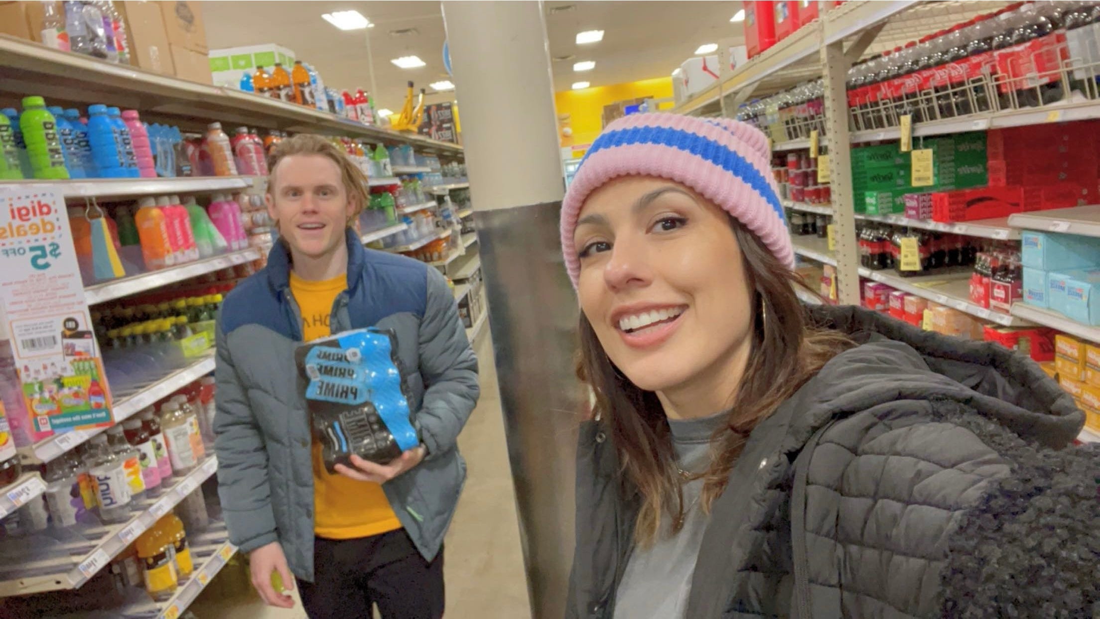 andrea valdez and brandon wells at the grocery store with a case of blue prime drinks