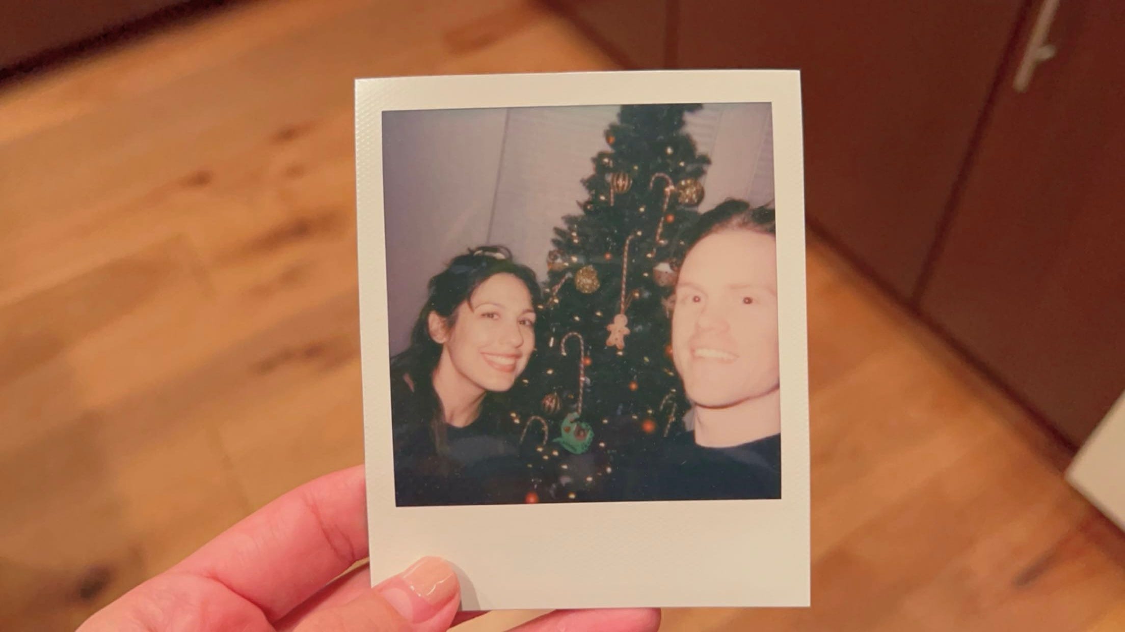 poloroid photo of andrea valdez and brandon wells in front of their xmas tree