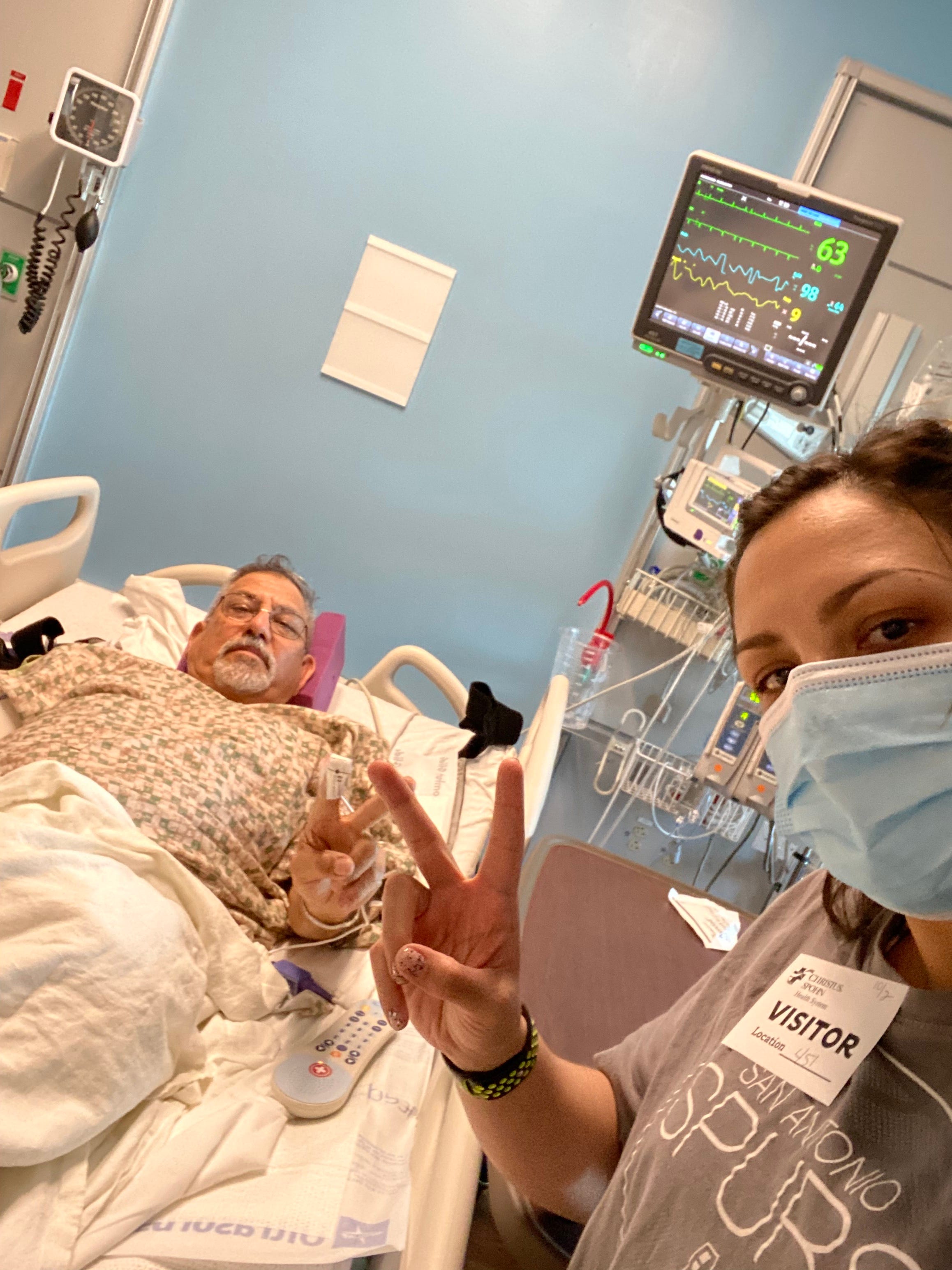 andrea valdez and her dad taking a selfie while he is in his hospital bed recovering from a heart attack